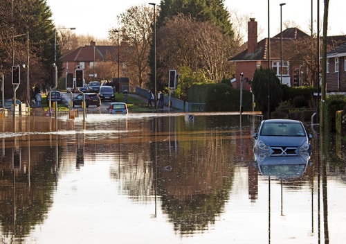 blue car trapped on flooded street