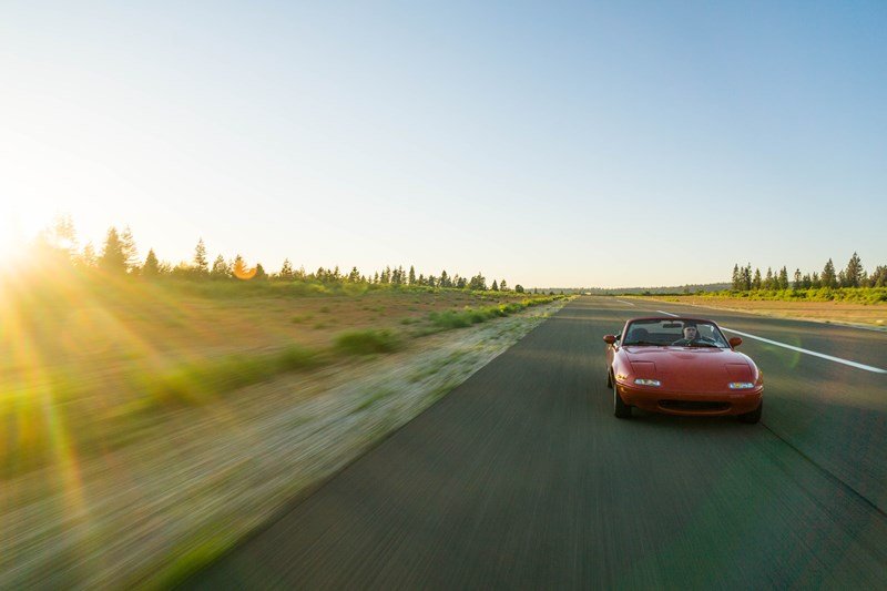 man driving red corvette on a sunny day